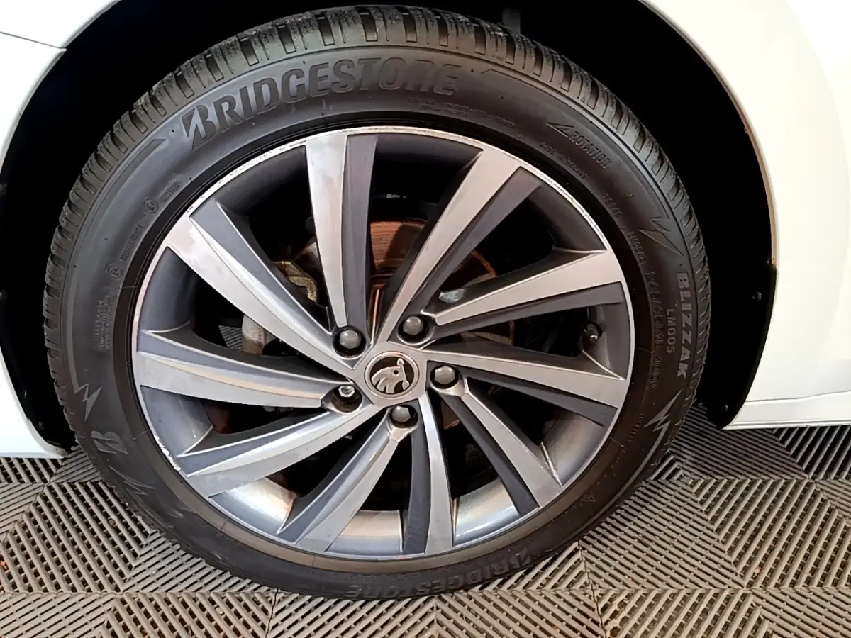 Gros plan sur la roue avant gauche blanche d’une Skoda Octavia 2.0 TDI 150 DSG7 Style avec jante alliage gris foncé.