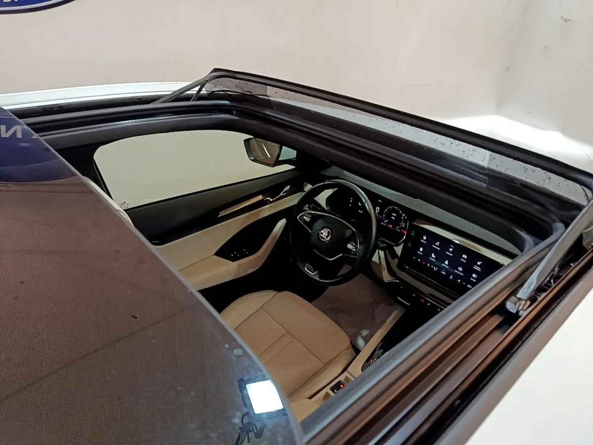 Vue plongeante sur l'intérieur beige et noir d'une Skoda Octavia 2022, avec tableau de bord digital et toit ouvrant.