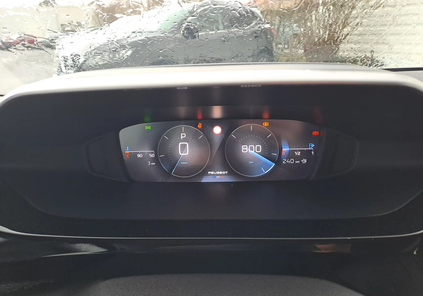 Vue rapprochée du tableau de bord numérique de la Peugeot 308 blanc Okenite, affichant la vitesse à 0 km/h et le régime moteur à 800 rpm.