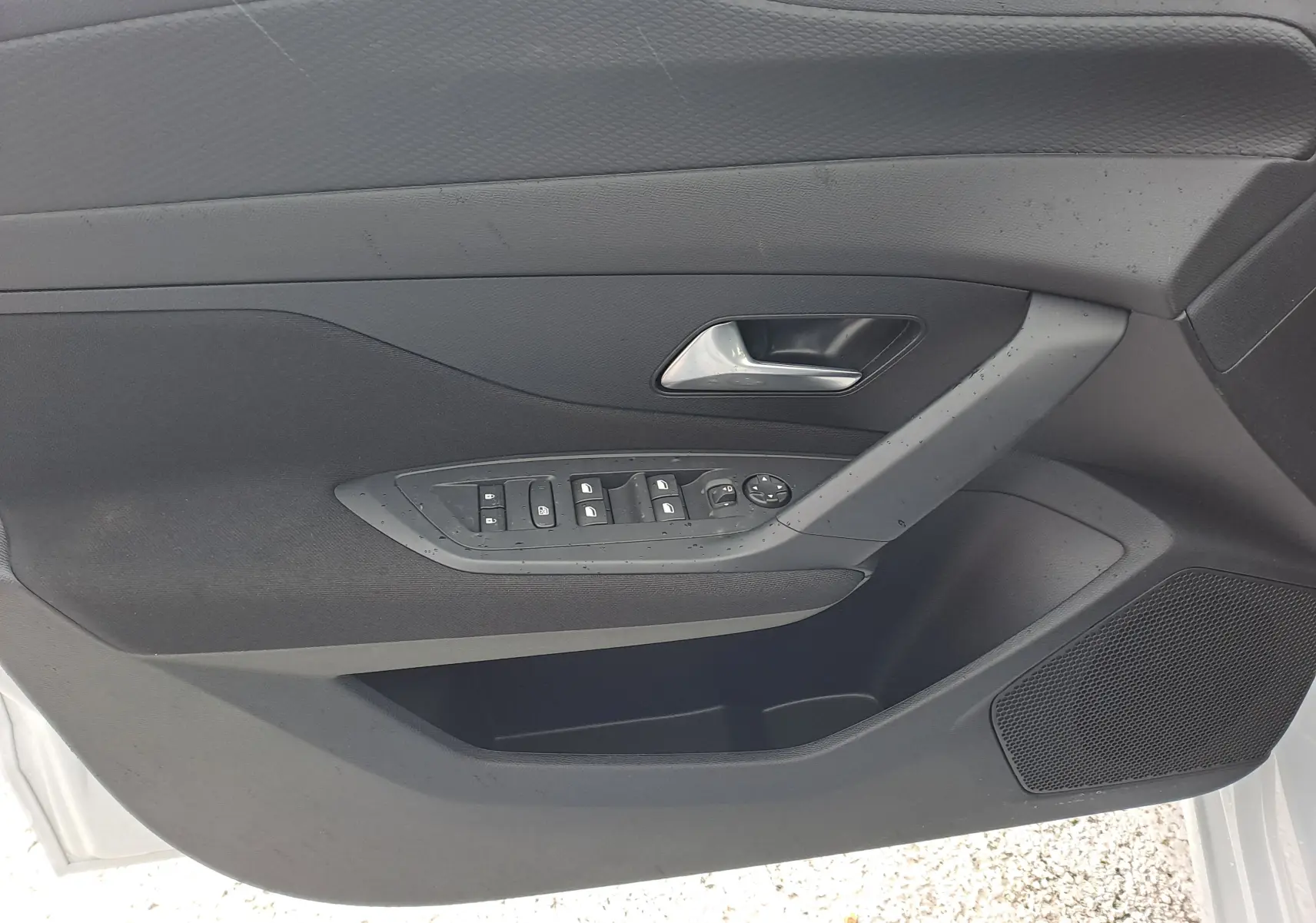 Intérieur de la porte avant gauche de la Peugeot 308 blanc Okenite, avec commandes des vitres et poignée argentée.