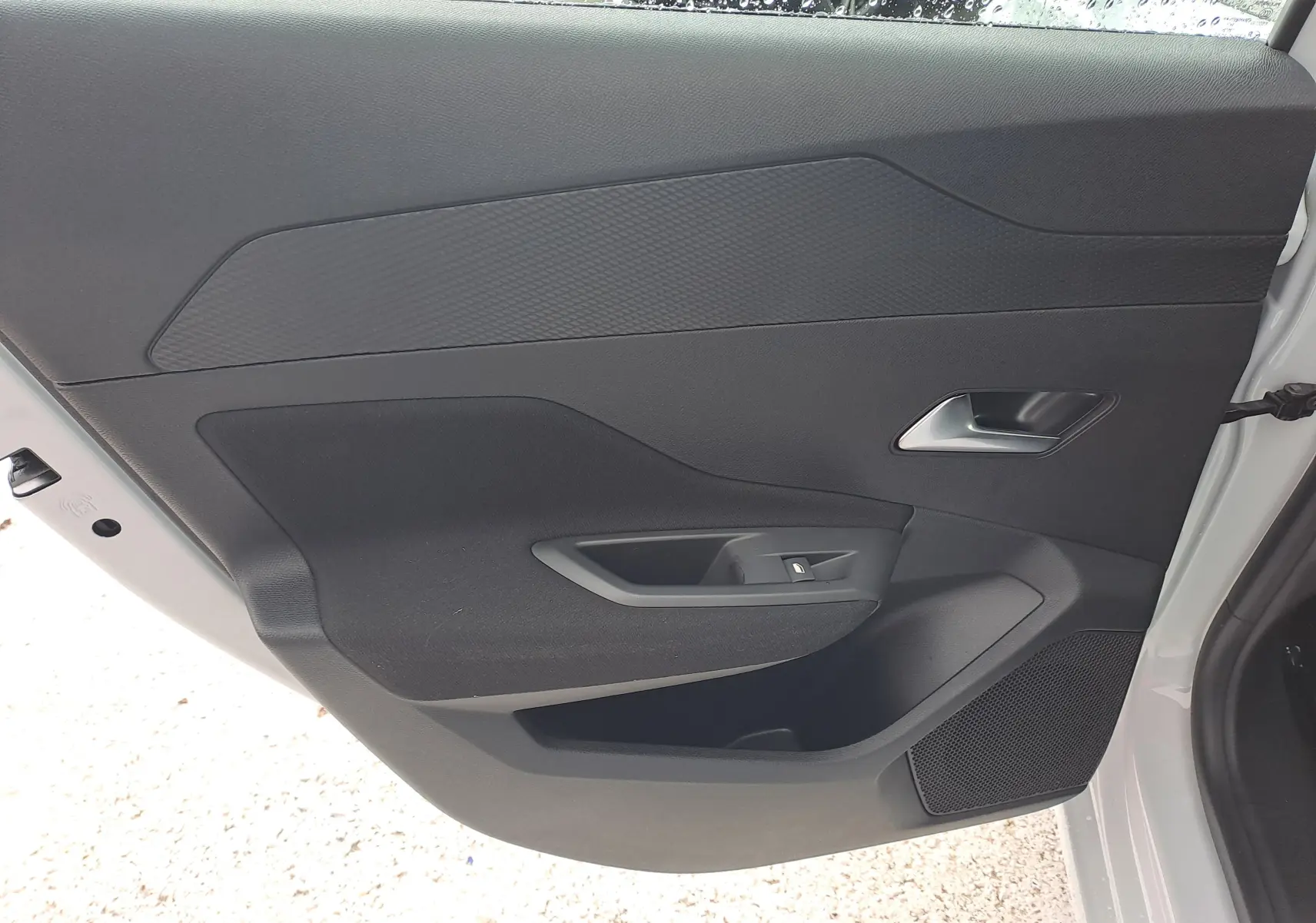 Vue intérieure de la porte arrière droite d'une Peugeot 308 blanche, avec poignée argentée et commande de vitre.