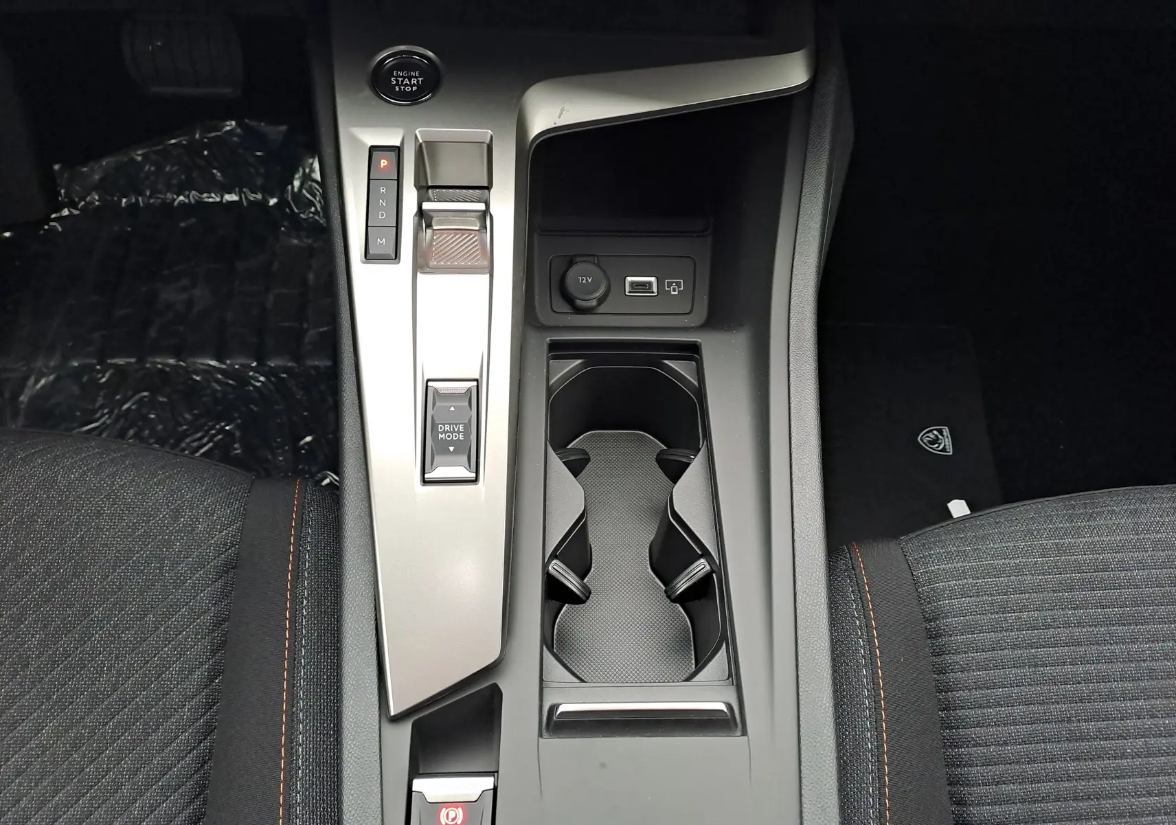 Vue plongeante sur la console centrale de la Peugeot 308 2025, avec levier de vitesses électronique et porte-gobelets.