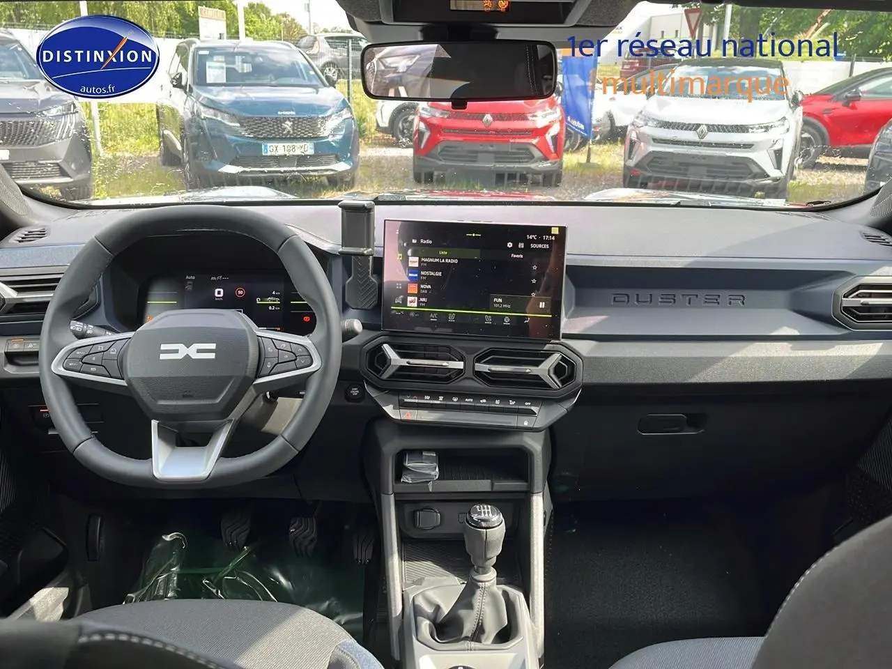 Vue intérieure avant du Dacia Duster gris schiste 2025, tableau de bord moderne avec écran tactile et volant multifonction.