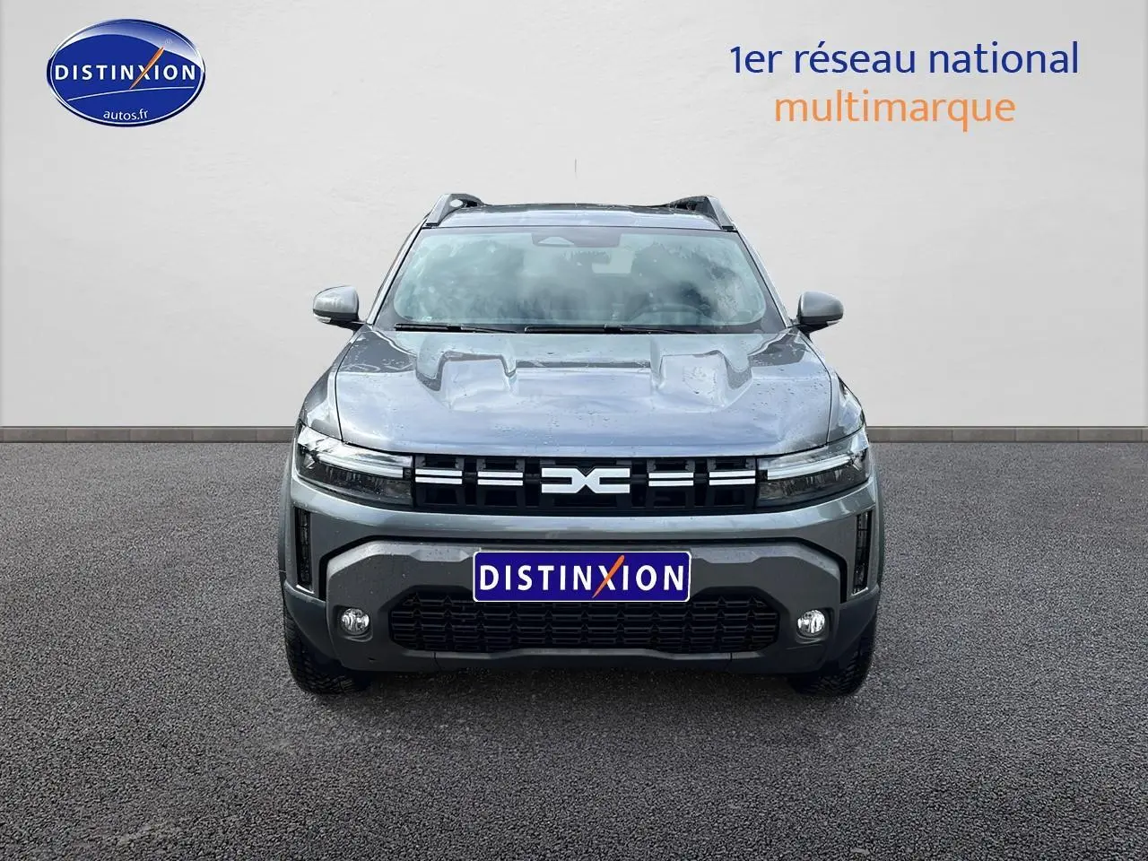 Vue frontale du Dacia Duster gris schiste 2025 avec calandre noire et logo central distinctif, sur fond neutre.