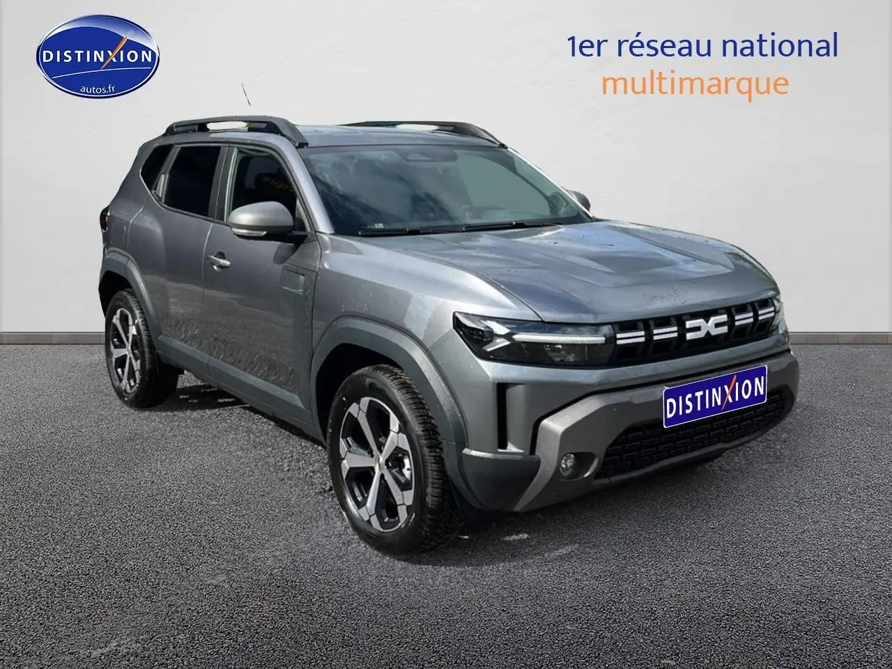 SUV Dacia Duster gris schiste vu en 3/4 avant droit avec barres de toit et jantes alu distinctives.