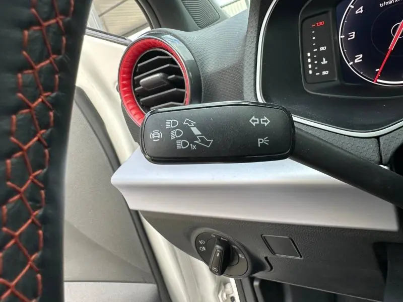 Gros plan sur la manette de clignotants et l’aération rouge du tableau de bord côté gauche d’une SEAT Ibiza blanche 2025.