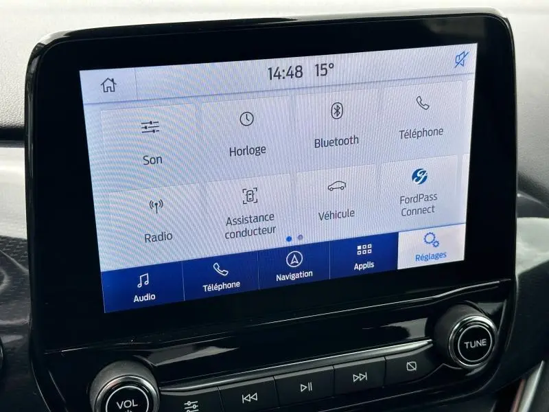 Écran tactile central du Ford Puma 2024 en noir Agate Métallisée, affichant le menu principal avec options audio et navigation.