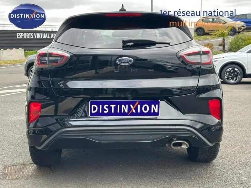 Vue arrière d'un Ford Puma 2024 noir agate métallisé avec feux arrière distinctifs et sortie d'échappement visible côté droit.
