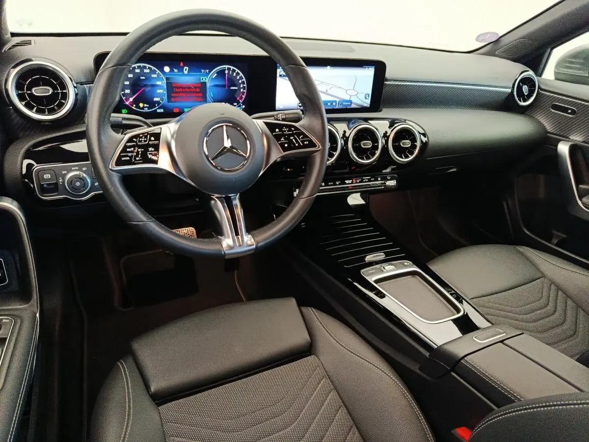 Vue intérieure avant de la Mercedes Classe A 250 e hybride, tableau de bord noir avec écran tactile et volant multifonctions.