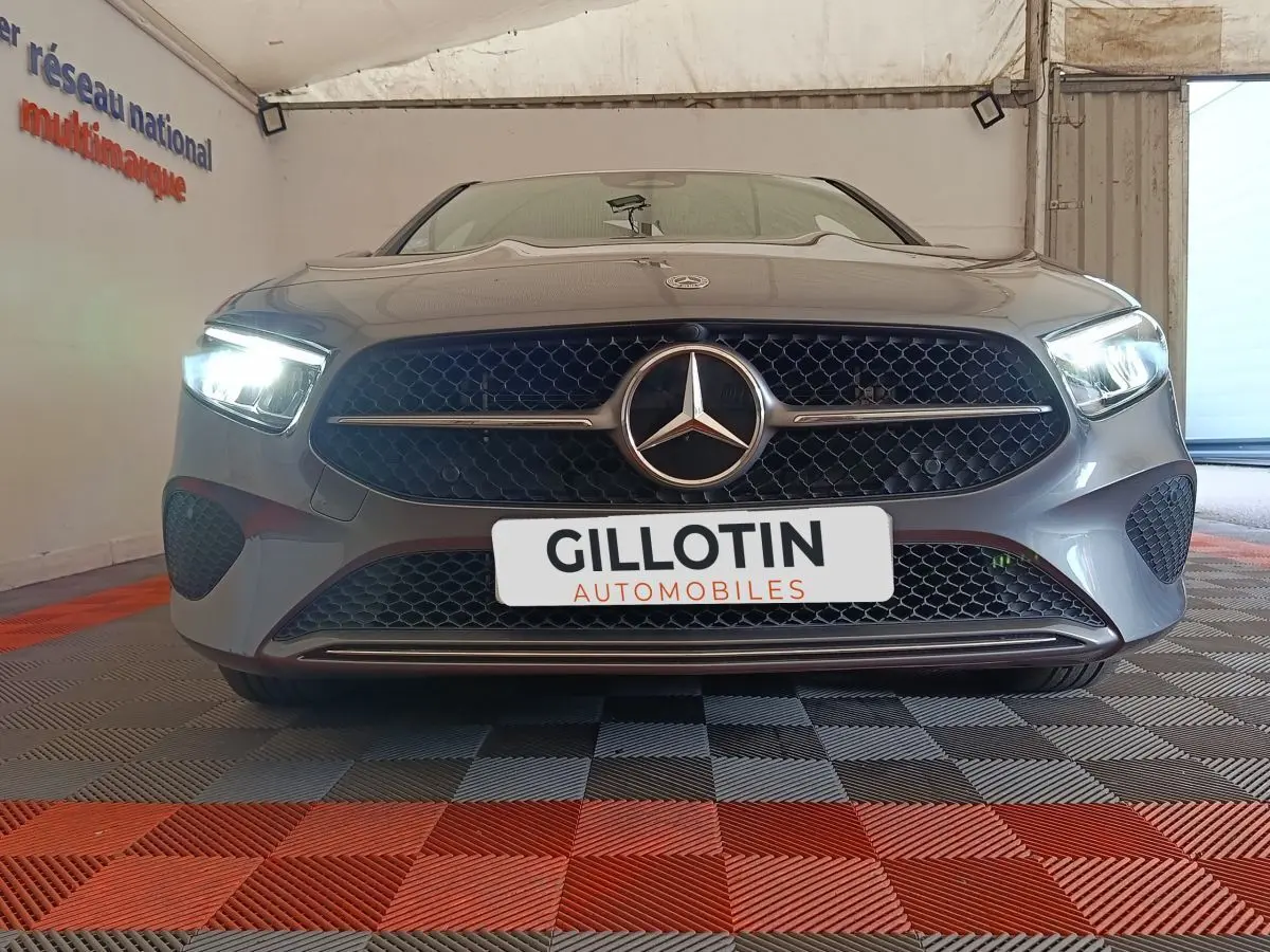 Vue frontale d'une Mercedes Classe A 250 e Hybrid gris foncé avec phares LED allumés en intérieur.