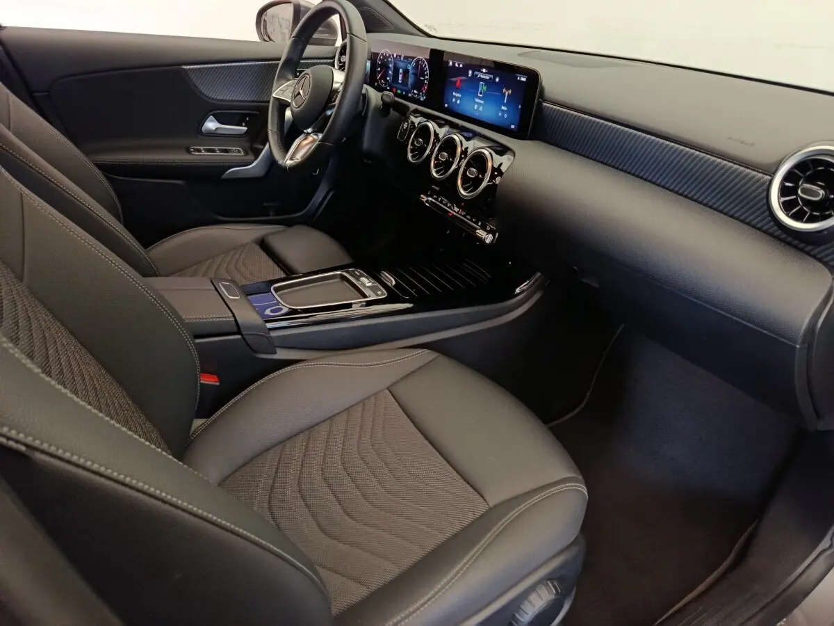 Intérieur avant droit de la Mercedes Classe A 250 e Hybrid 2024, tableau de bord numérique et sièges gris foncé.
