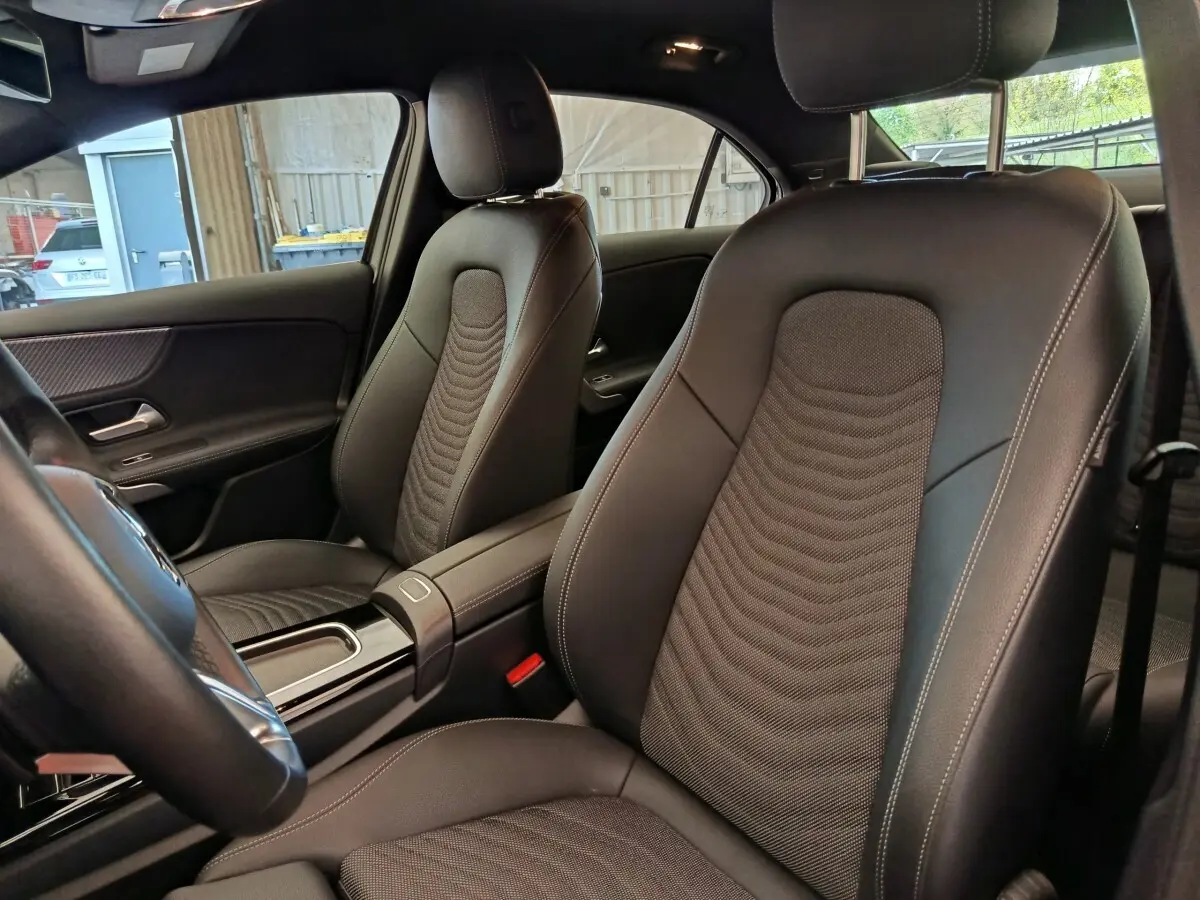 Vue intérieure côté avant droit de la Mercedes Classe A 250 e Hybrid, sièges en cuir noir avec surpiqûres contrastées.