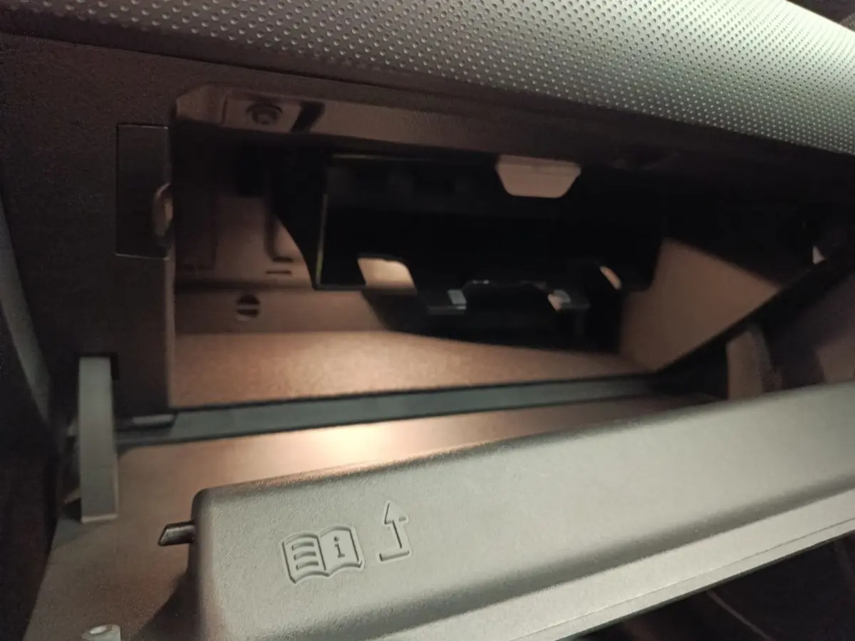 Vue rapprochée de la boîte à gants ouverte dans l’habitacle gris foncé de la Mercedes Classe A 250 e Hybrid 2024.