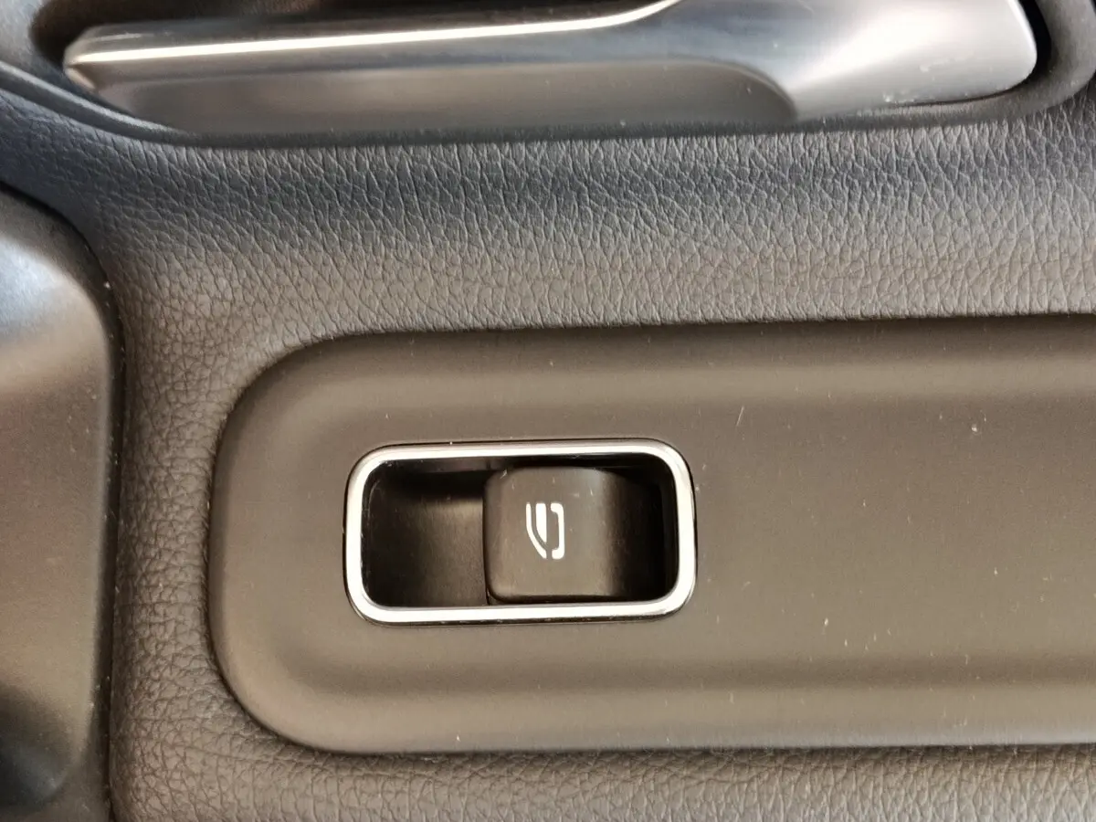 Gros plan sur le bouton de commande de la fermeture électrique du hayon dans l’habitacle gris foncé de la Mercedes Classe A 250 e Hybrid.
