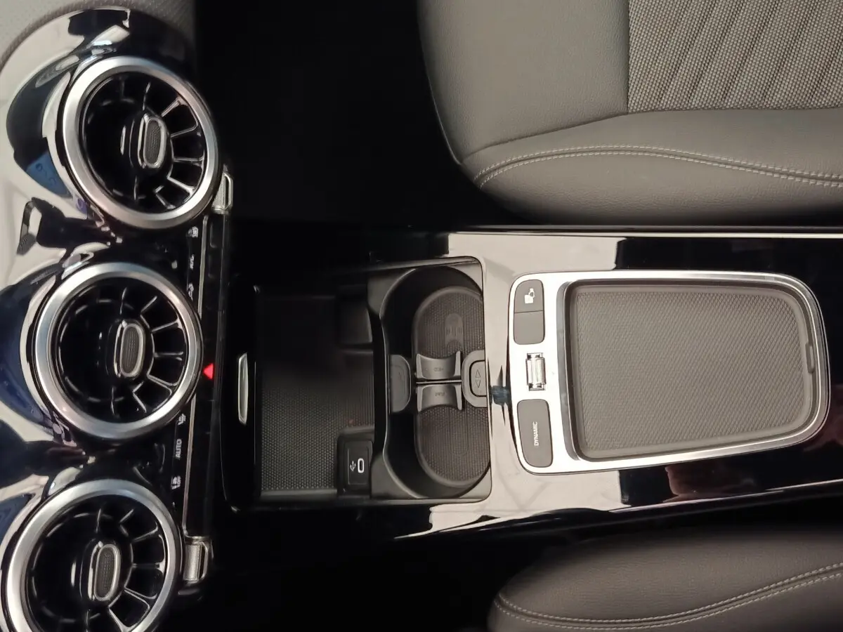 Vue plongeante sur la console centrale noire brillante de la Mercedes Classe A 250 e Hybrid avec aérateurs ronds chromés.
