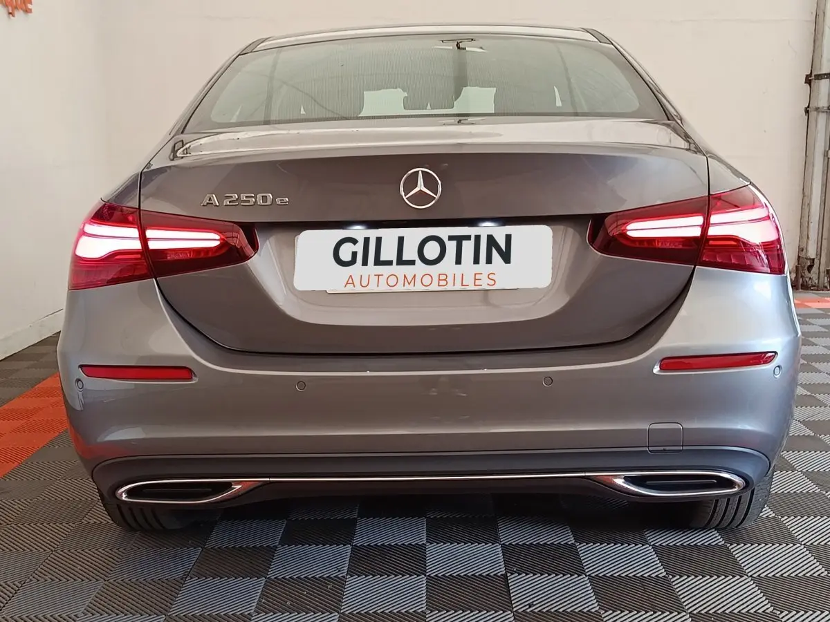 Vue arrière d'une Mercedes Classe A 250 e hybride rechargeable gris foncé avec feux LED allumés et double sortie d'échappement chromée.