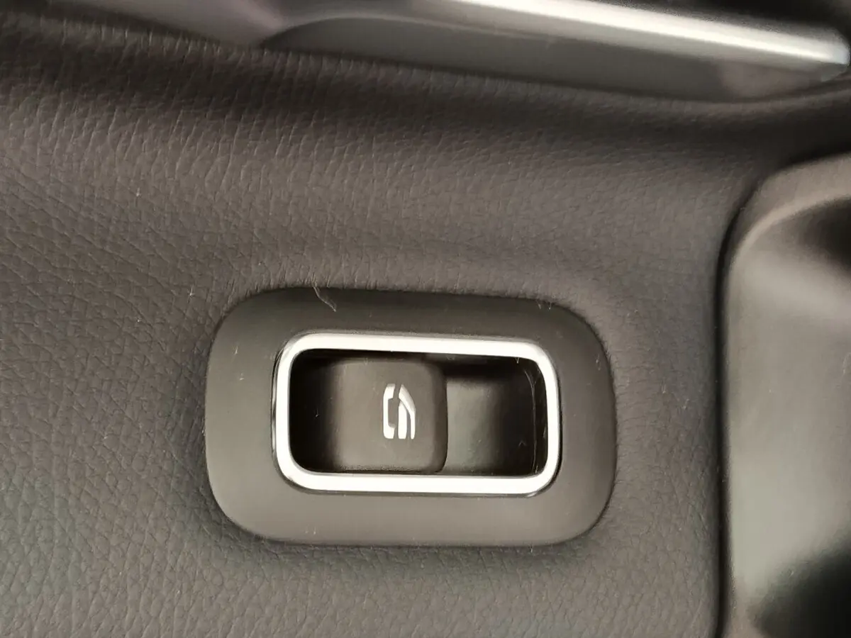 Bouton de commande de hayon électrique sur panneau intérieur noir d'une Mercedes Classe A 250 e Hybrid gris foncé.