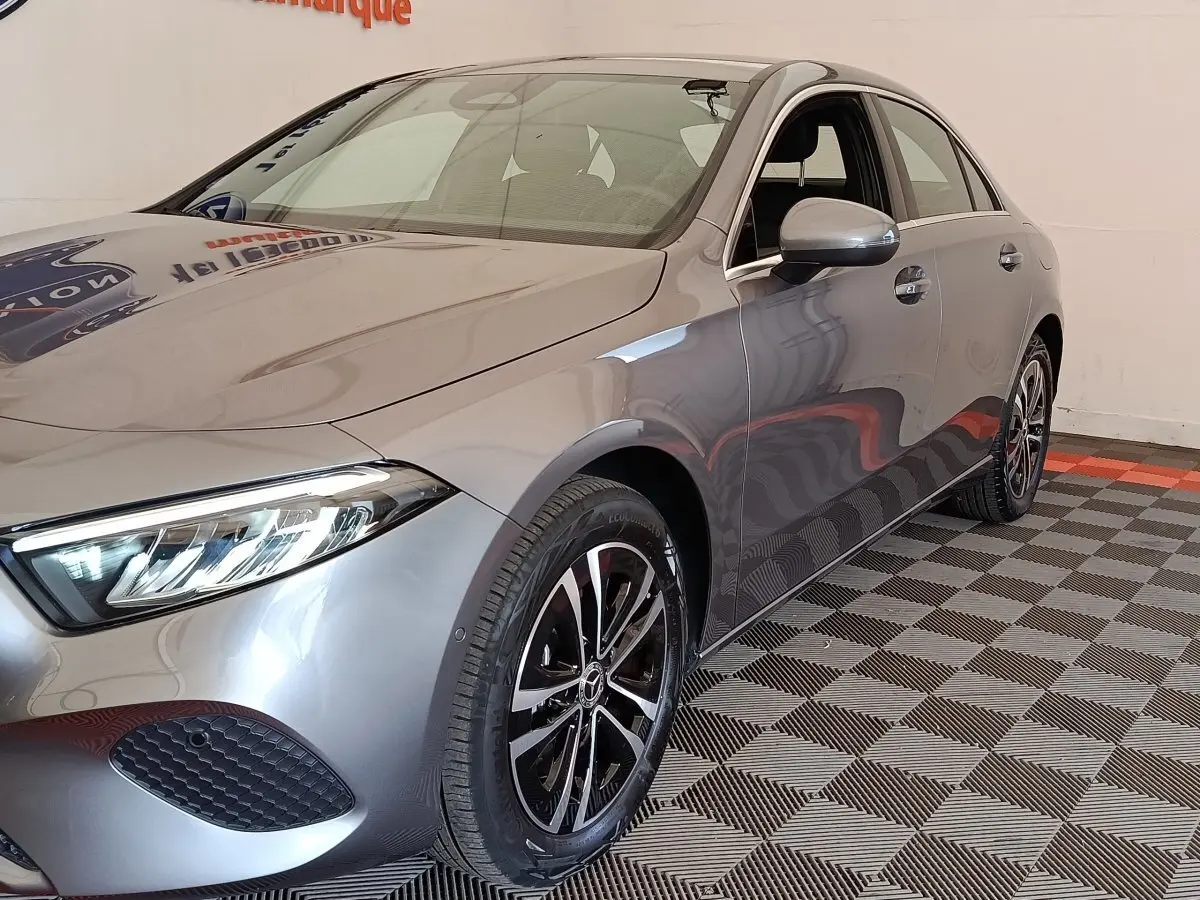 Mercedes Classe A 250 e hybride gris foncé vue 3/4 avant droit avec jantes alliage et phares LED allumés.