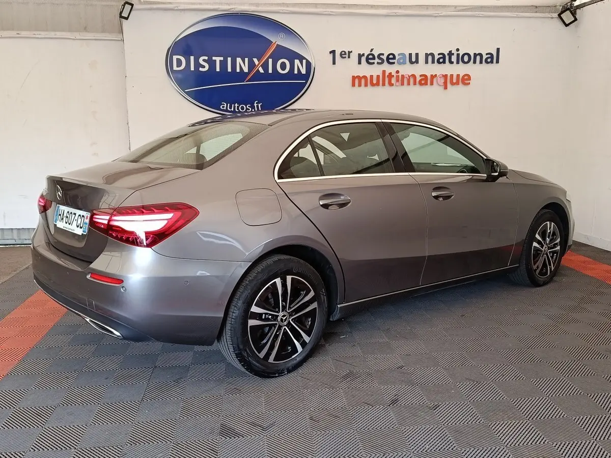 Vue 3/4 arrière droite d'une Mercedes Classe A 250 e hybride rechargeable gris foncé avec feux LED allumés.