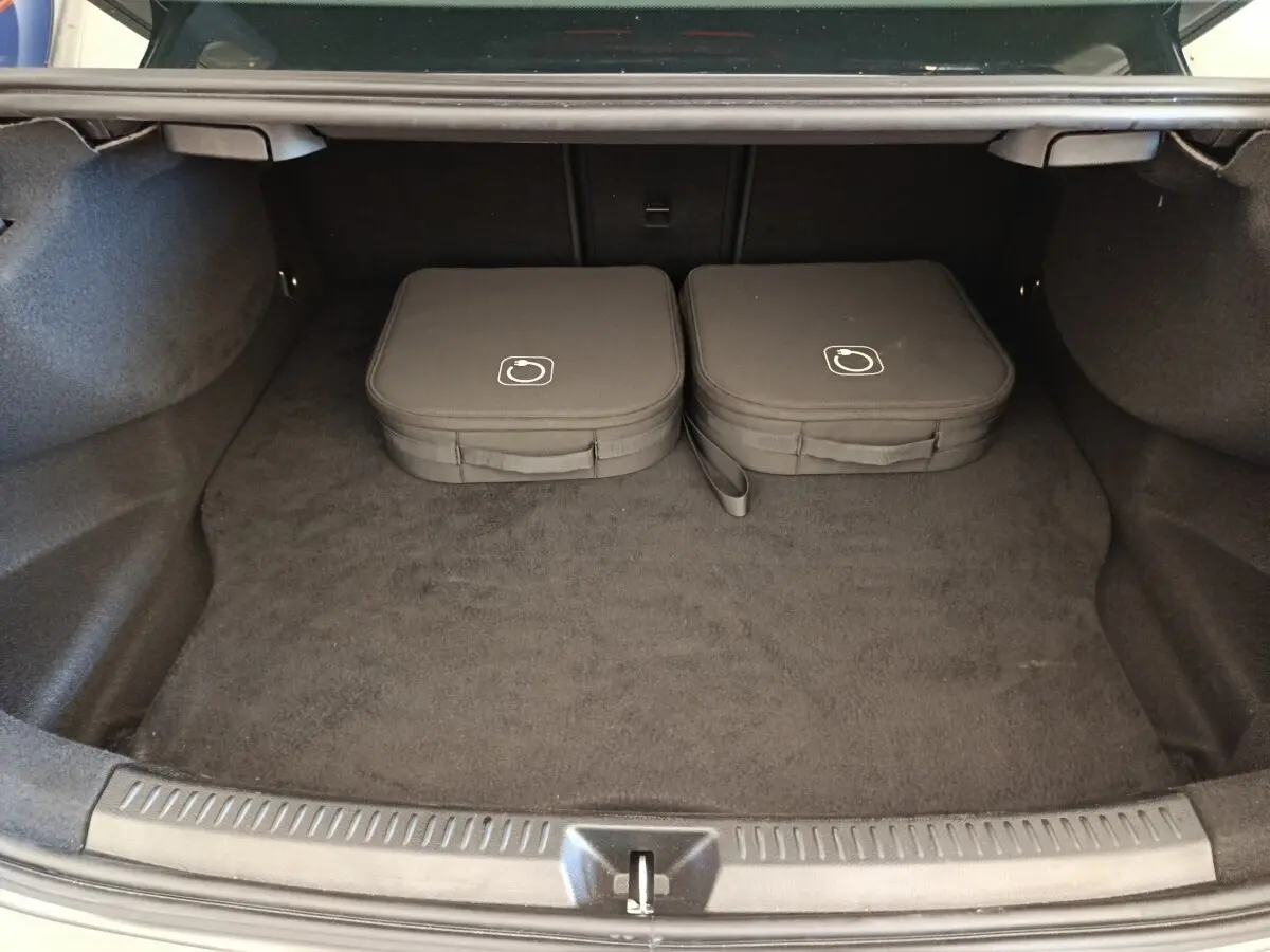 Coffre ouvert d’une Mercedes Classe A 250 e hybride gris foncé, avec deux sacs de charge posés à l’intérieur.