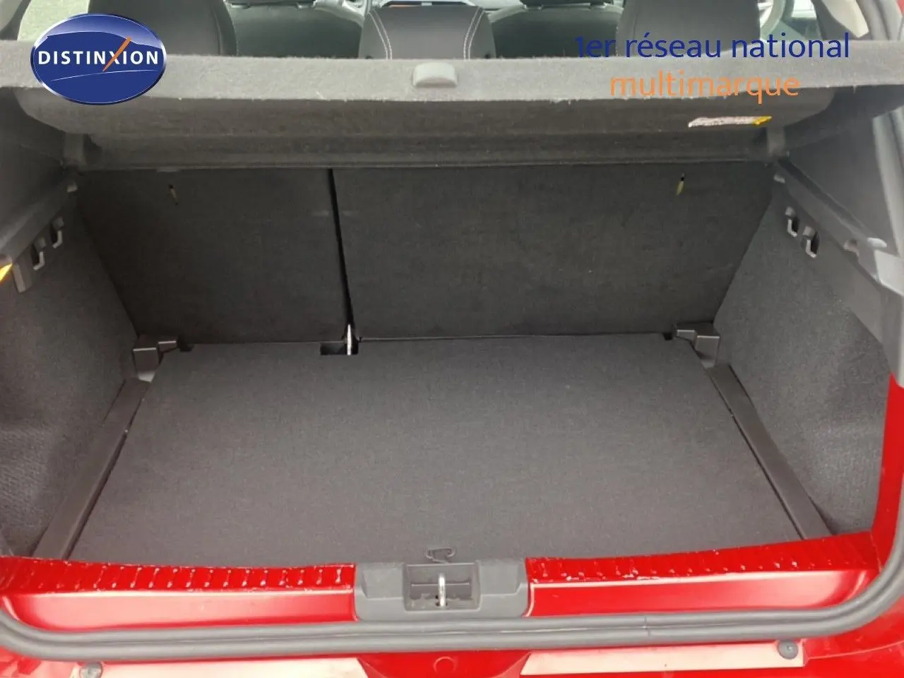 Coffre ouvert vu de l'arrière d'une Dacia Sandero Stepway rouge fusion métal, montrant l'espace de chargement vide.