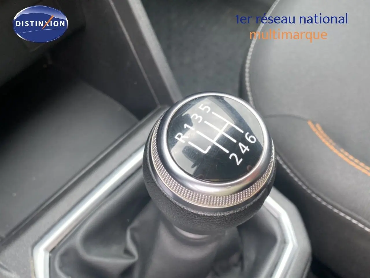 Gros plan sur le levier de vitesses manuel de la Dacia Sandero Stepway rouge fusion, avec coutures orange visibles sur le siège.