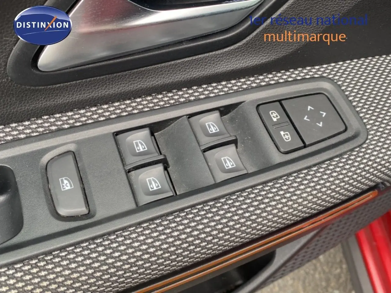 Gros plan sur les commandes des vitres électriques côté conducteur d'une Dacia Sandero rouge fusion métal 2022.