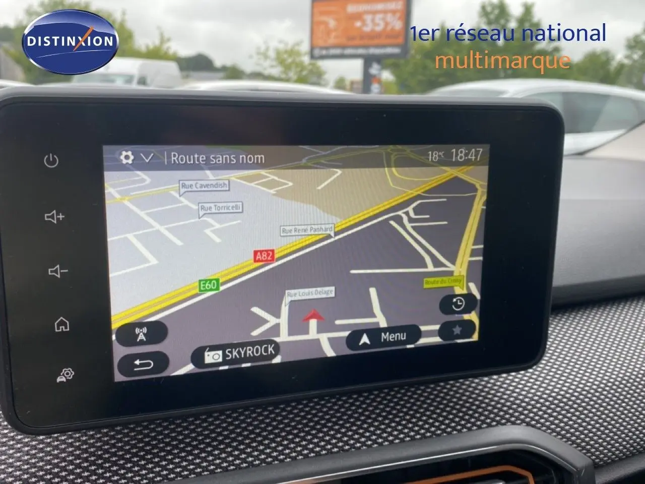 Écran tactile central du tableau de bord de la Dacia Sandero rouge, affichant la navigation GPS en extérieur.