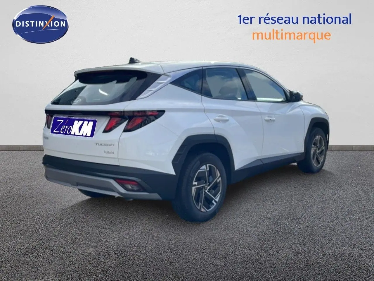 Hyundai Tucson blanc atlas en 3/4 arrière droit, SUV hybride avec jantes alliage et feux arrière LED distinctifs.
