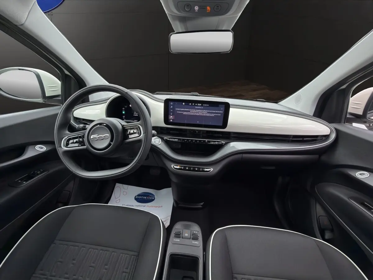 Intérieur avant de la FIAT 500 blanc, vue centrée sur le tableau de bord avec écran tactile et volant multifonctions.