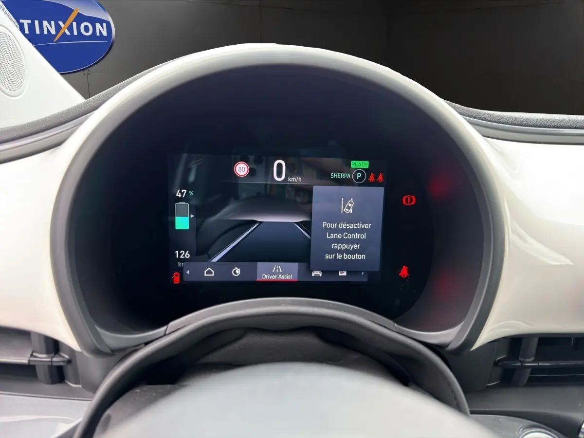 Vue rapprochée du combiné d'instruments numérique de la Fiat 500 blanche 2023, affichant l'assistance au maintien de voie.