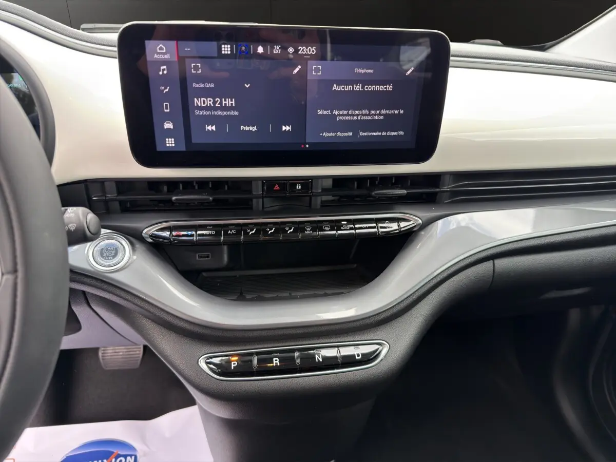 Vue intérieure du tableau de bord de la Fiat 500 blanche, avec écran tactile central et commandes de climatisation.