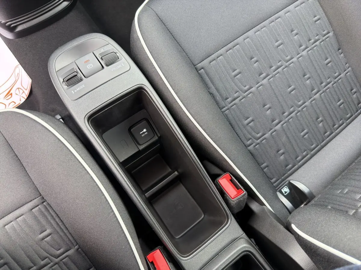 Vue rapprochée de la console centrale et des sièges gris foncé avec surpiqûres blanches d'une Fiat 500 électrique blanche.