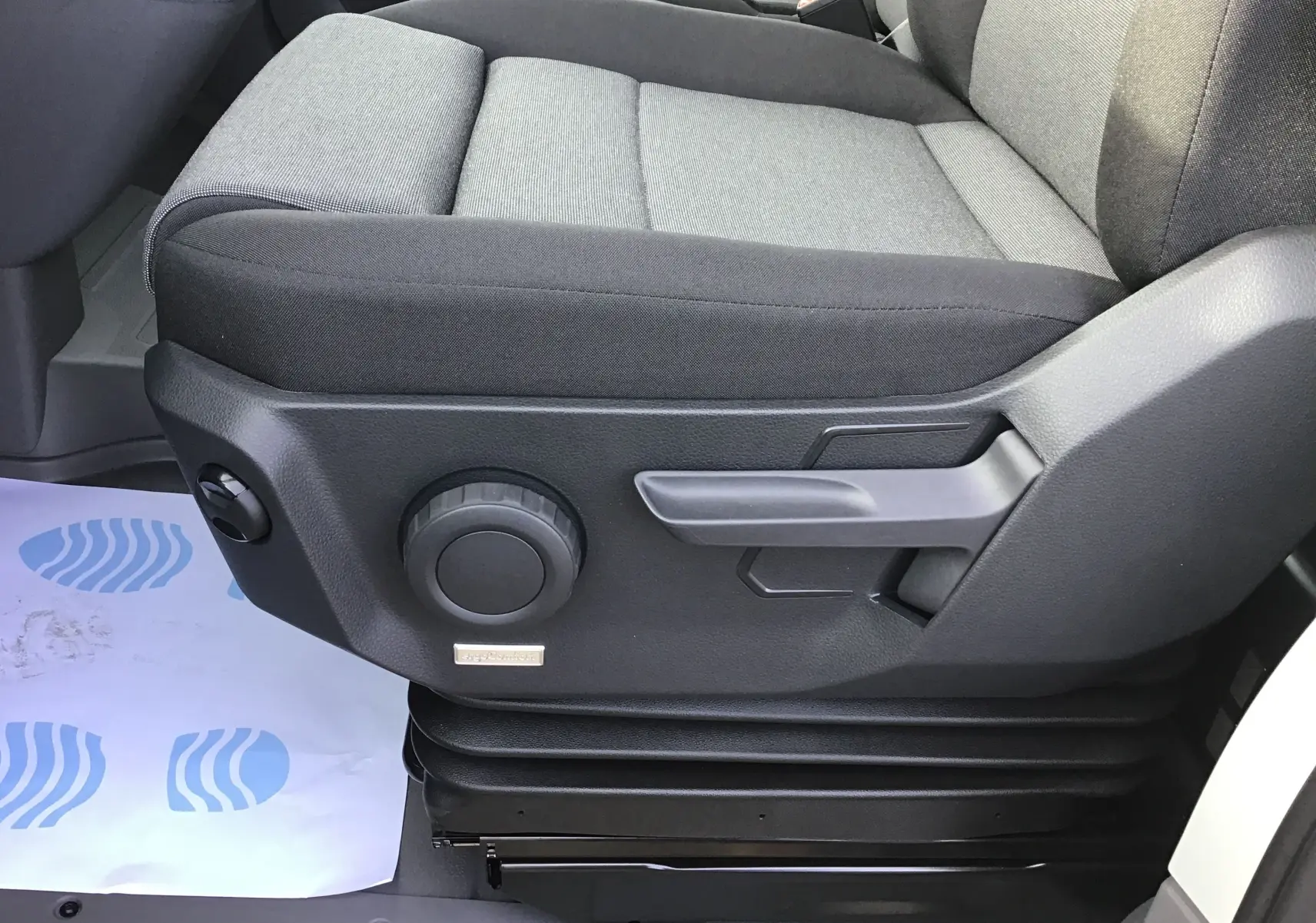 Gros plan côté gauche du siège conducteur gris à réglage manuel du Volkswagen Crafter blanc 2024 avec suspension Ergo Confort.