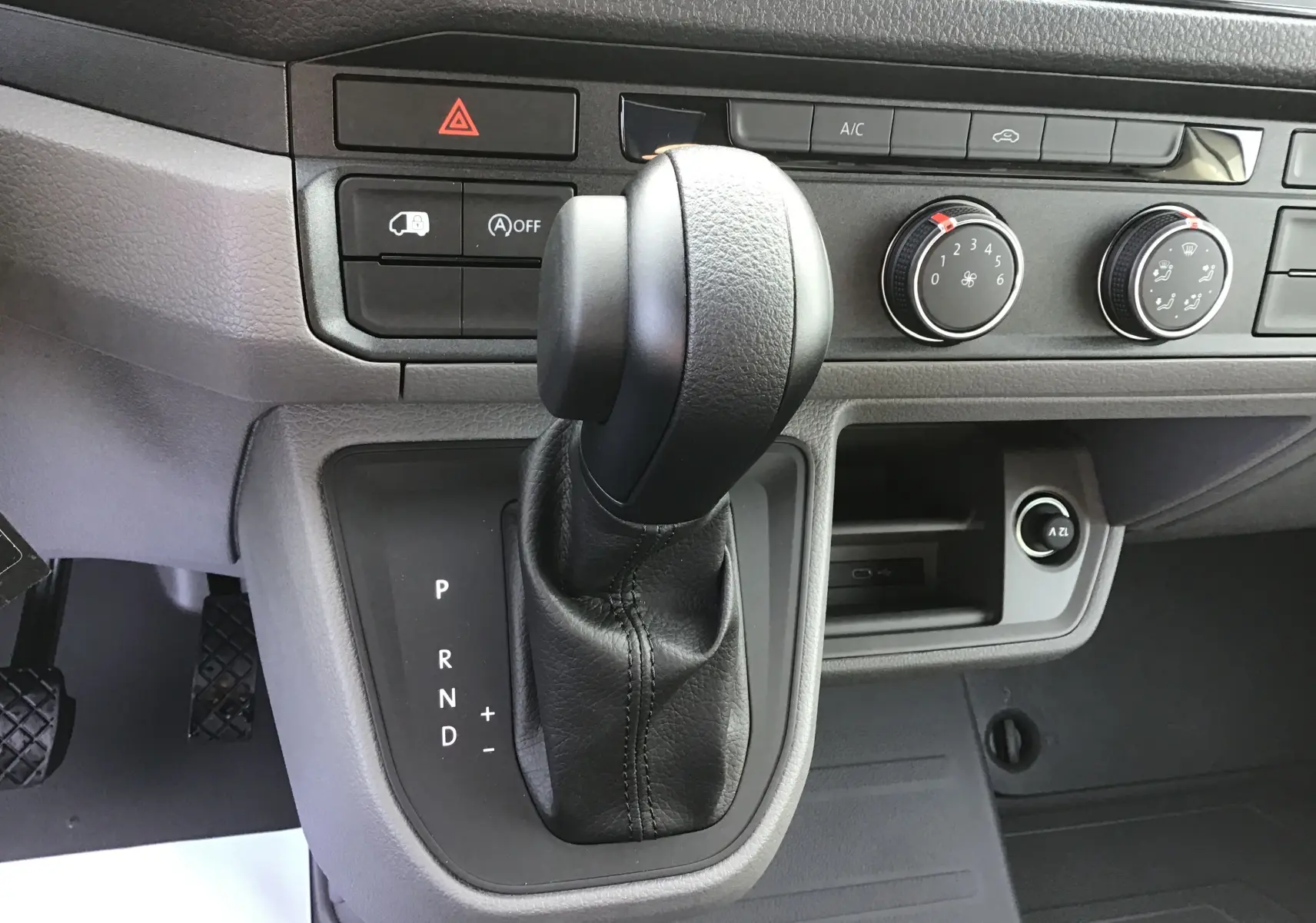 Le levier de vitesses automatique noir du Volkswagen Crafter Fourgon 2024, avec commandes de climatisation et tableau de bord gris.