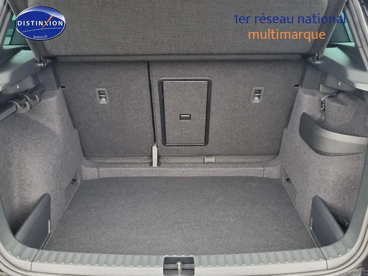 Coffre ouvert d’un Skoda Karoq noir 2025, montrant la banquette arrière avec trappe à skis centrale.