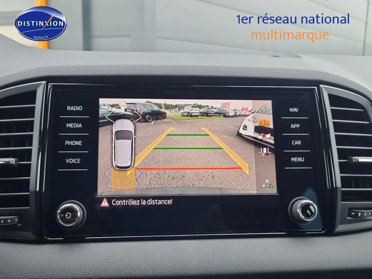 Écran tactile intérieur montrant la caméra de recul du Skoda Karoq noir, avec lignes d’aide au stationnement colorées.