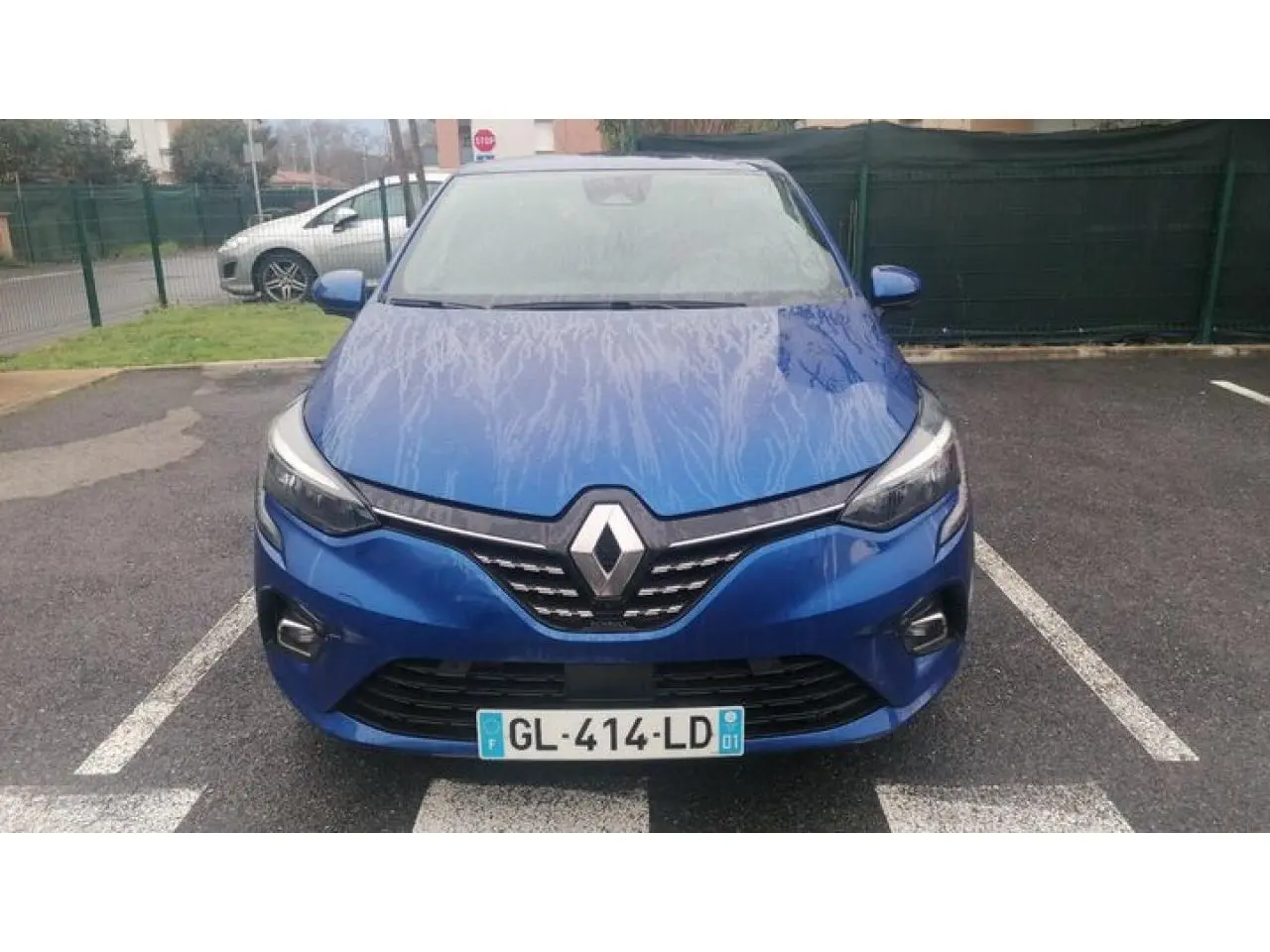 Vue avant d'une Renault Clio 1.0 Tce Intens 2021 en bleu Iron avec logo Renault et phares allumés.