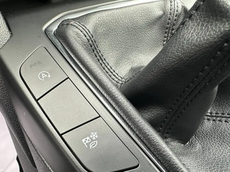 Gros plan sur la console centrale en cuir noir du Ford Kuga 1.5 EcoBoost, montrant le levier de vitesse manuel et les boutons de contrôle.