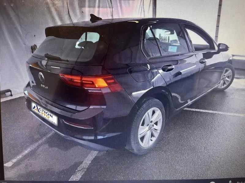 Volkswagen Golf noir intense nacrée vue 3/4 arrière droit, feux arrière LED allumés, jantes alliage visibles.