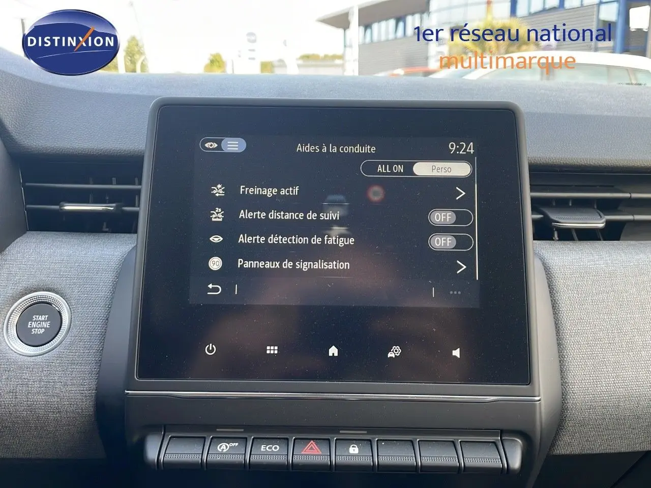 Écran tactile central de la Renault Clio gris schiste, affichant les aides à la conduite, avec bouton start/stop à gauche.