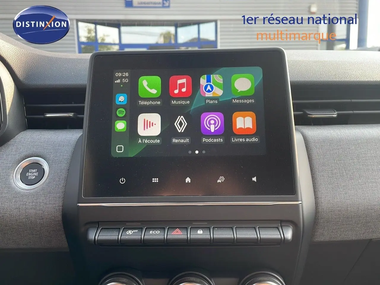Vue intérieure centrée sur l'écran tactile multimédia de la Renault Clio gris schiste, avec bouton start/stop à gauche.