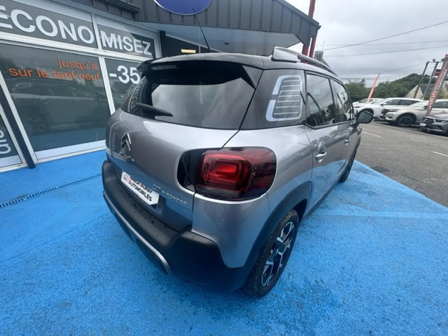 Vue 3/4 arrière droite du Citroën C3 Aircross gris acier avec toit noir et feux arrière foncés.