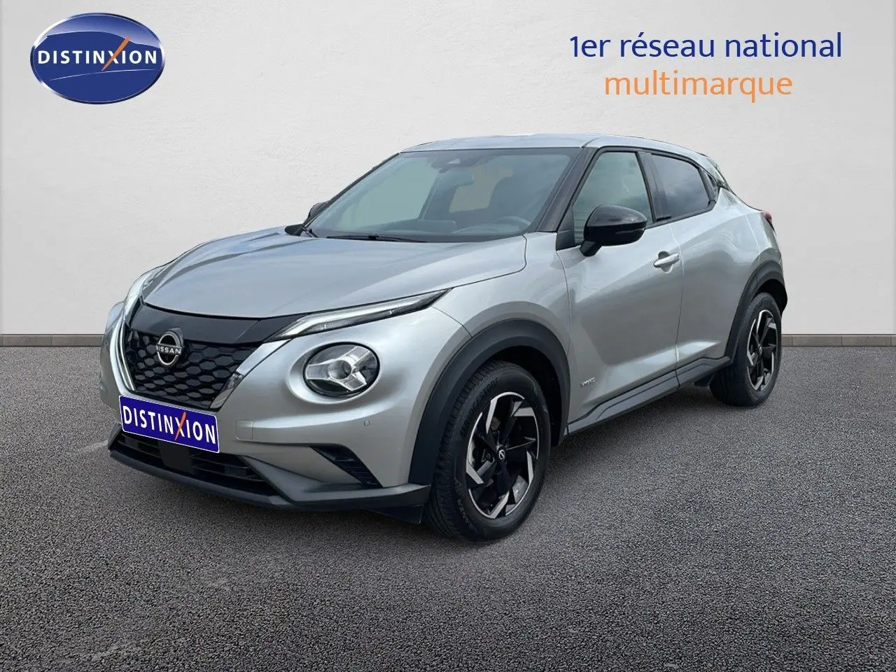 Nissan Juke Hybrid gris perle métal en 3/4 avant droit, avec jantes noires et détails noirs contrastants.