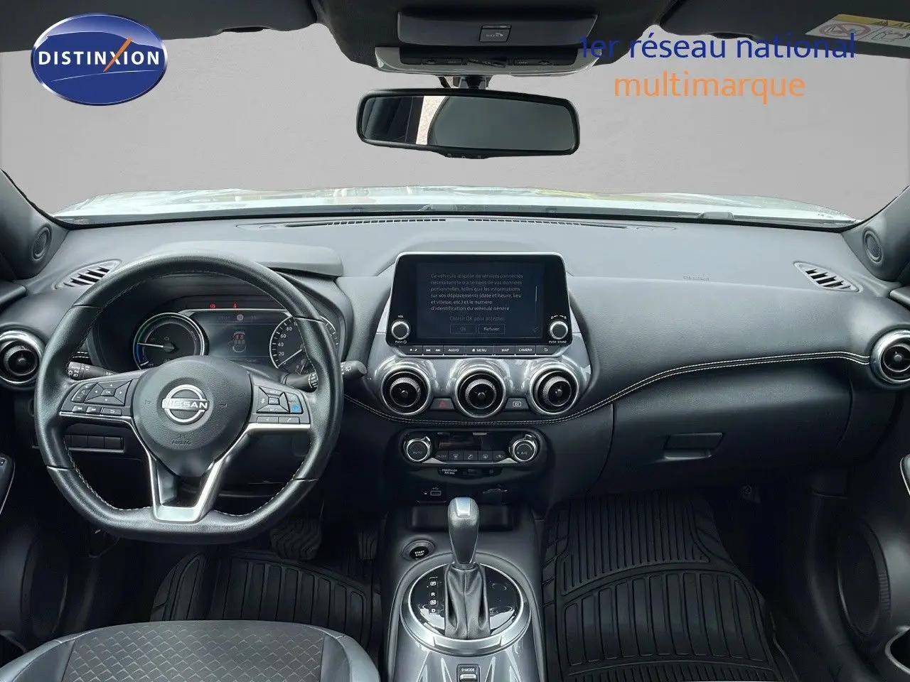 Intérieur du Nissan Juke Hybrid 2023 vu de face, tableau de bord noir avec écran tactile et volant multifonction.