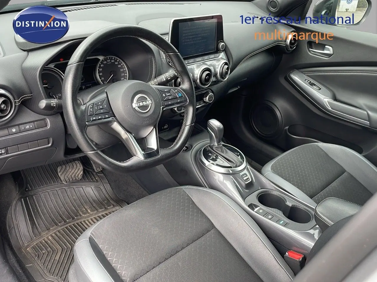 Intérieur avant droit du Nissan Juke Hybrid 143ch Business 2023 avec sellerie gris perle et console centrale brillante.