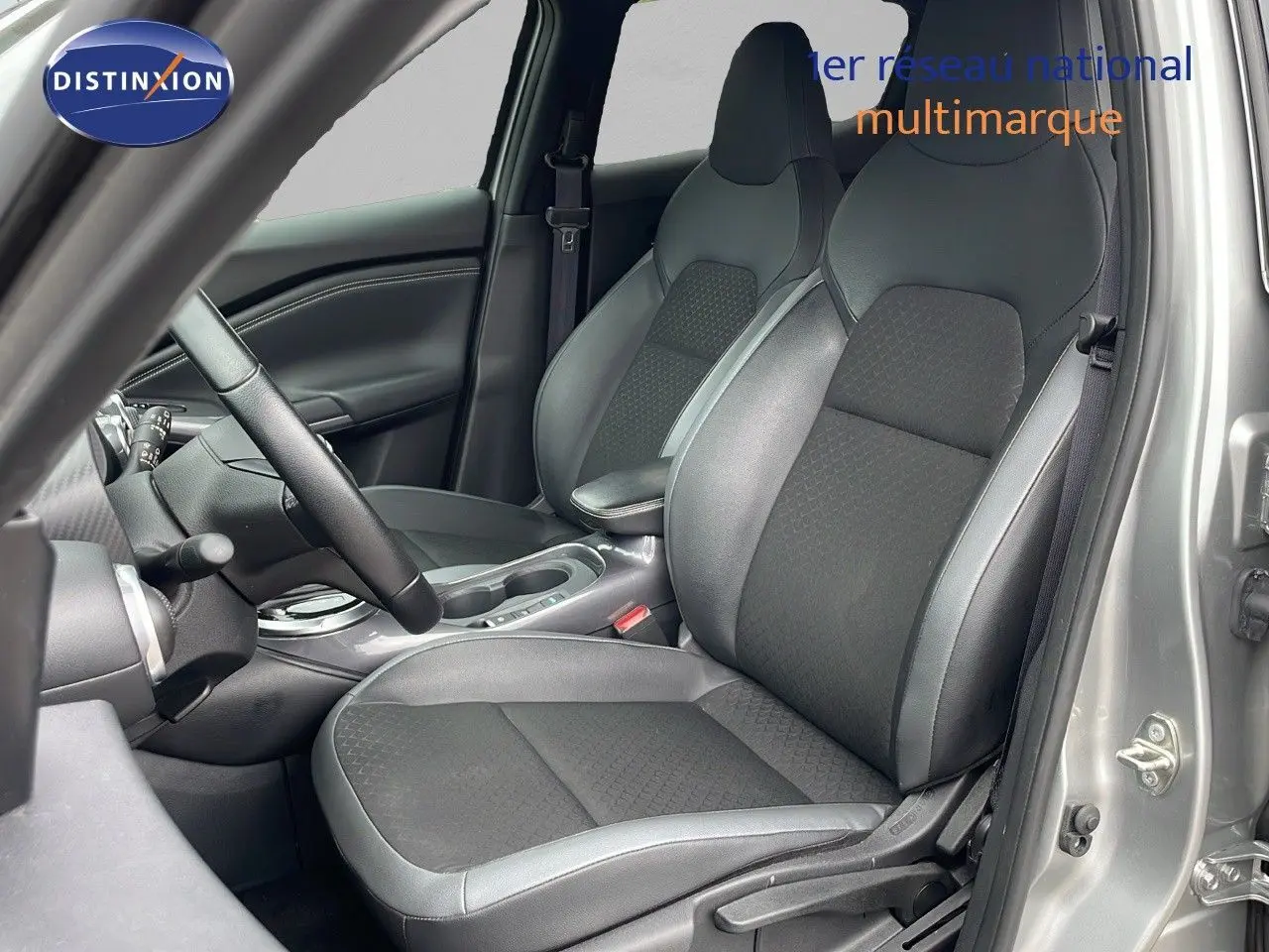 Vue intérieure côté conducteur du Nissan Juke Hybrid 143ch Business 2023 avec sièges en cuir gris et tissu noir.