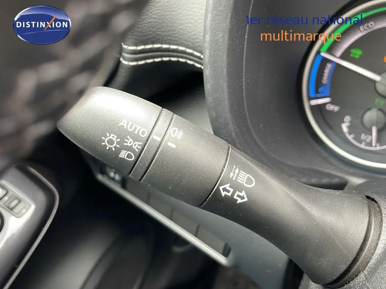 Gros plan sur la commande des feux et clignotants du Nissan Juke Hybrid 2023 avec tableau de bord partiellement visible.