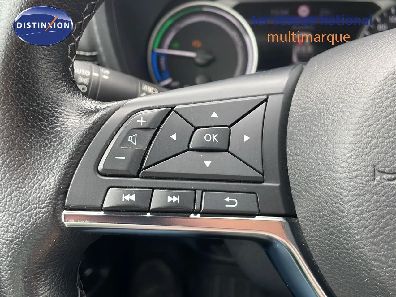 Gros plan sur les commandes au volant du Nissan Juke Hybrid 2023, avec cuir noir et tableau de bord partiellement visible.