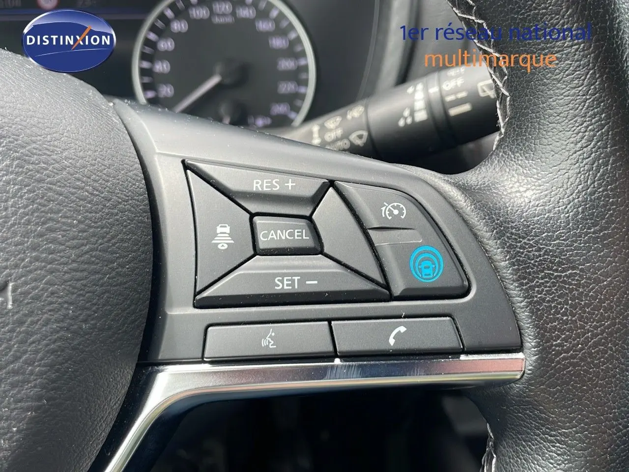 Gros plan sur les commandes au volant en cuir noir du Nissan Juke Hybrid 2023, avec boutons de régulateur de vitesse et appel.